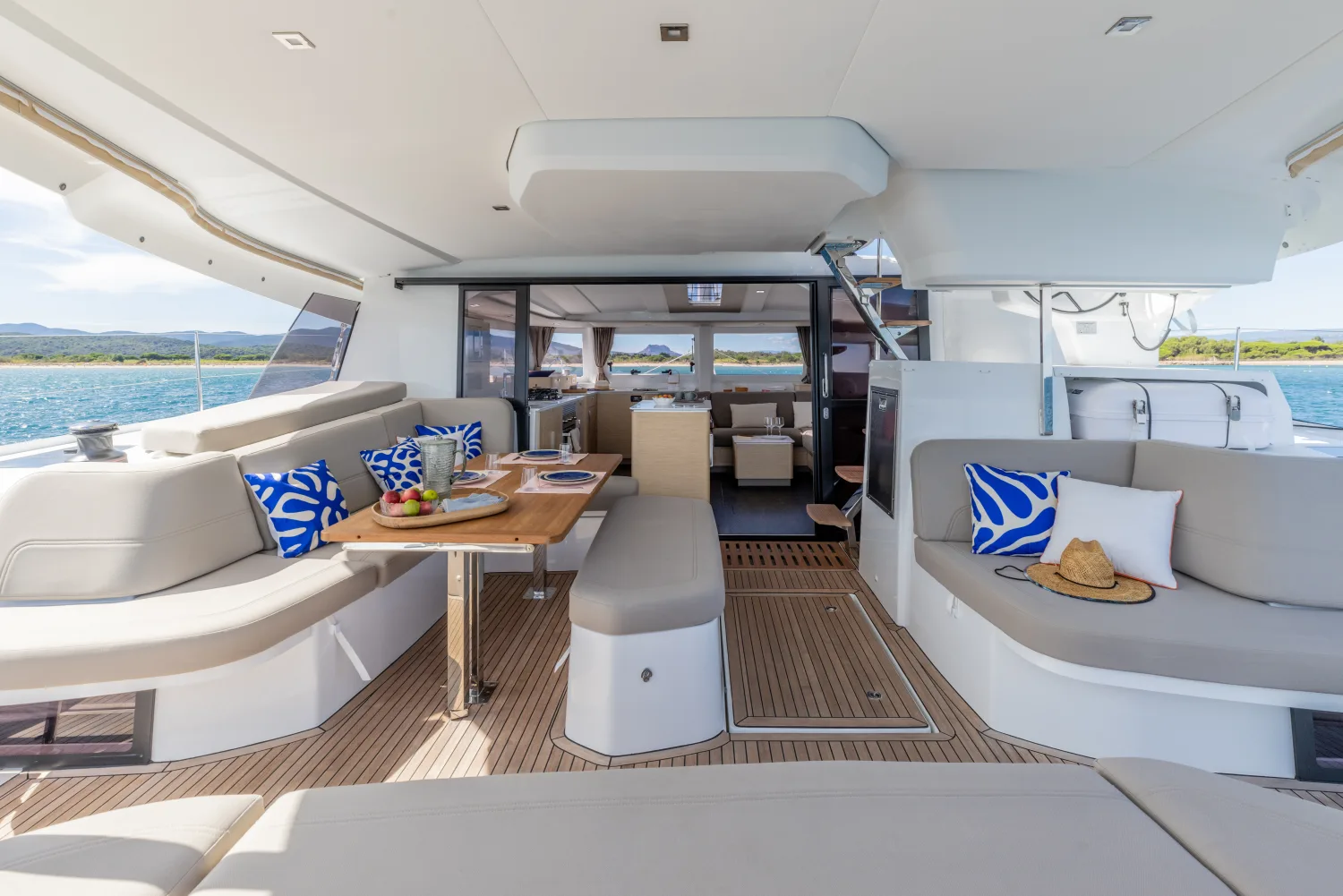 Cockpit-Lounge eines Katamarans mit Blick durch den Salon aufs Meer